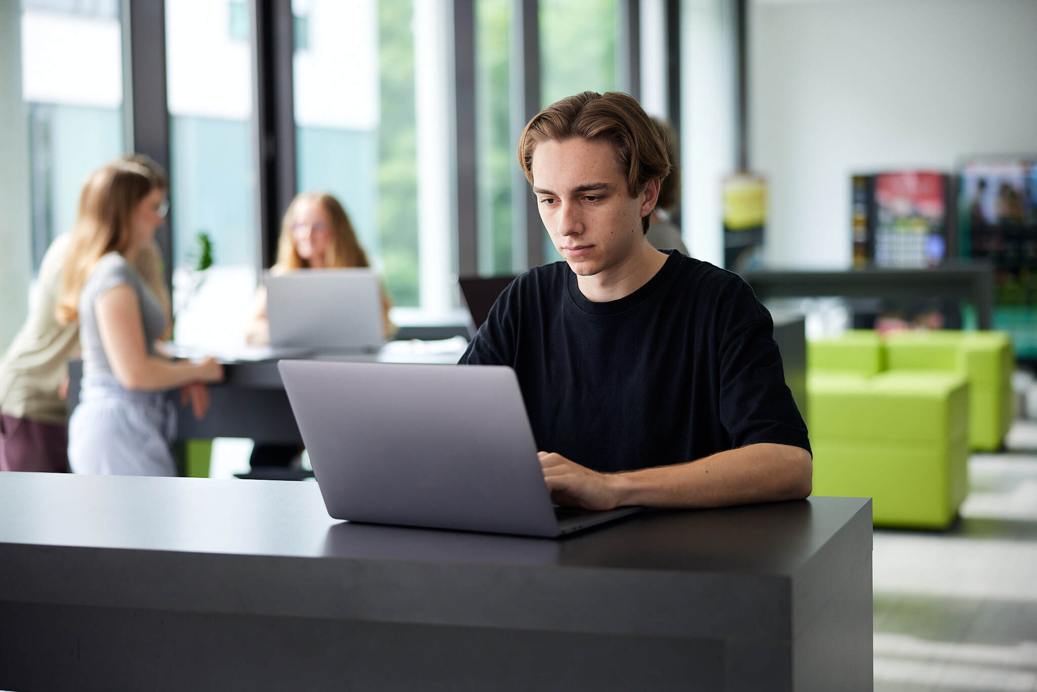 Ein junger Student arbeitet auf seinem Laptop in einem Aufenthaltsraum der FH Hagenberg