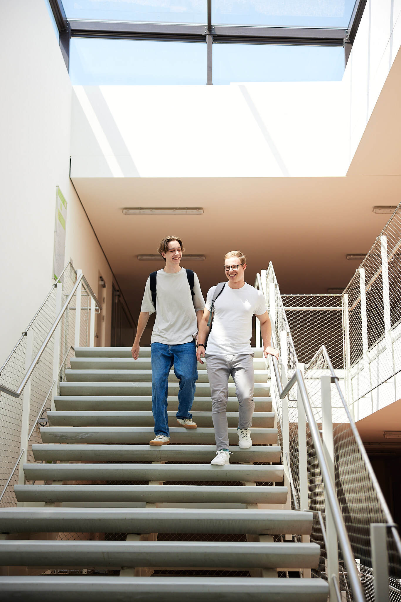 Zwei junge Studenten gehen gemeinsam auf einer Treppe in der FH Hagenberg hinunter