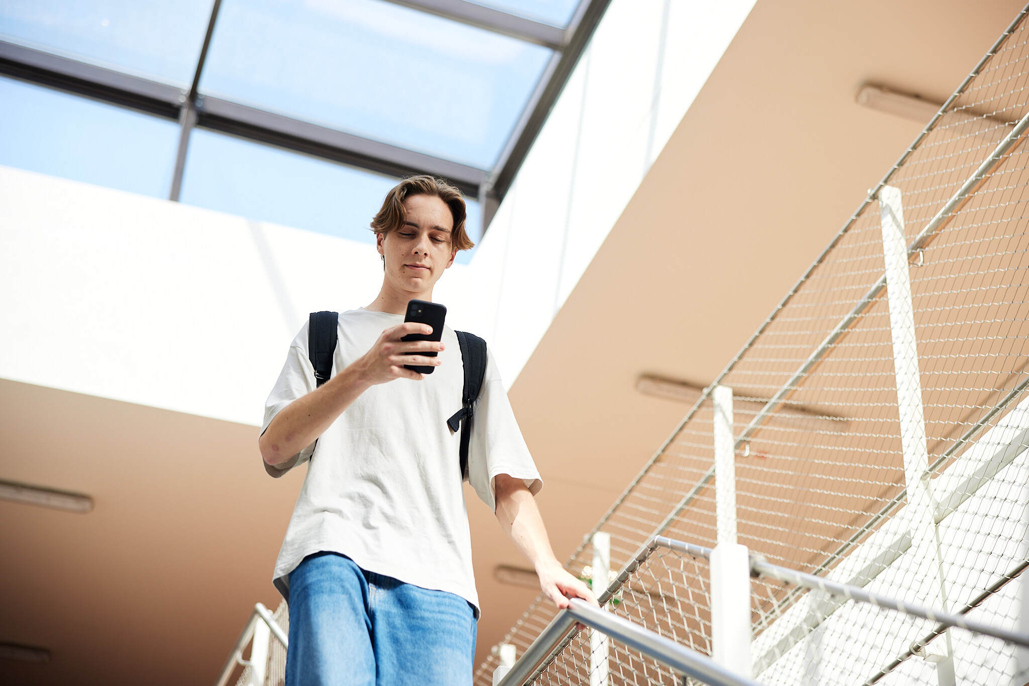Ein junger Student wird auf der Froschperspektive abgebildet wie er eine Treppe in der FH Hagenberg hinunter geht