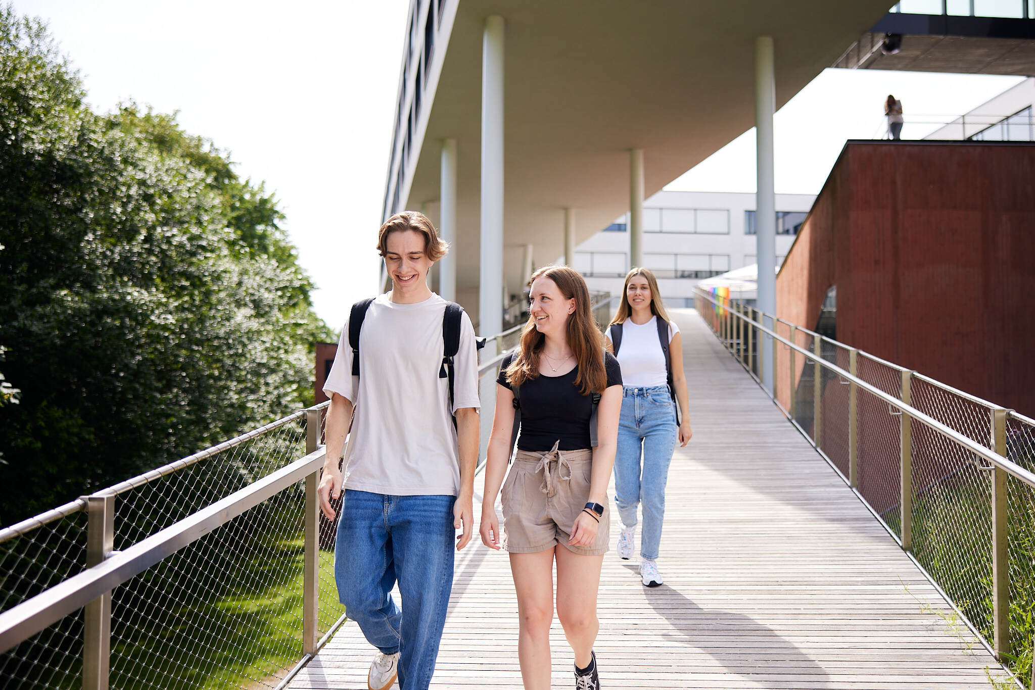 Drei junge Studenten die gemeinsam einen Steg am Campus Hagenberg hinunter gehen.