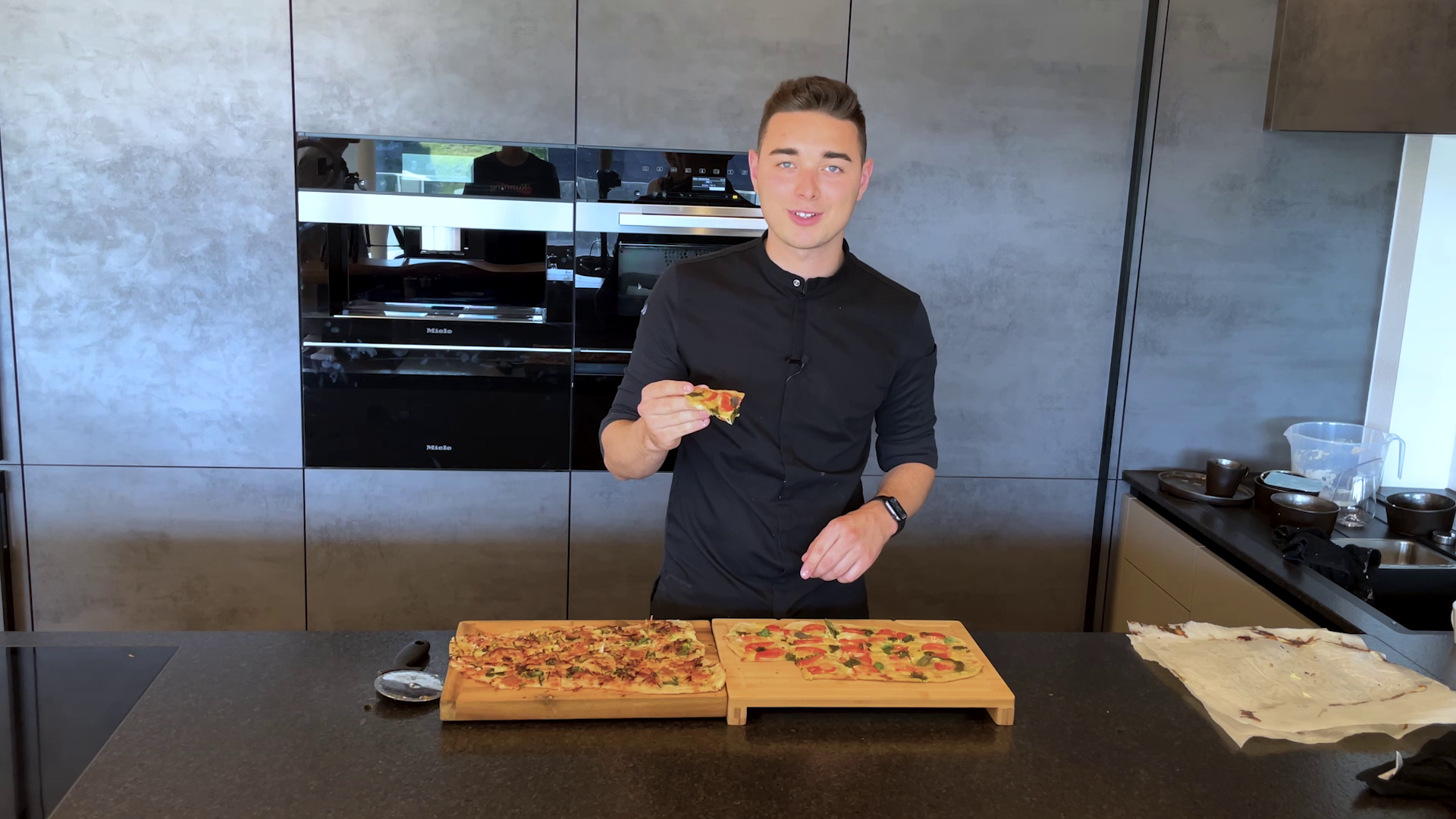 In einer Küche wird die selbstgebackene Pizza von einem Studenten verkostet.