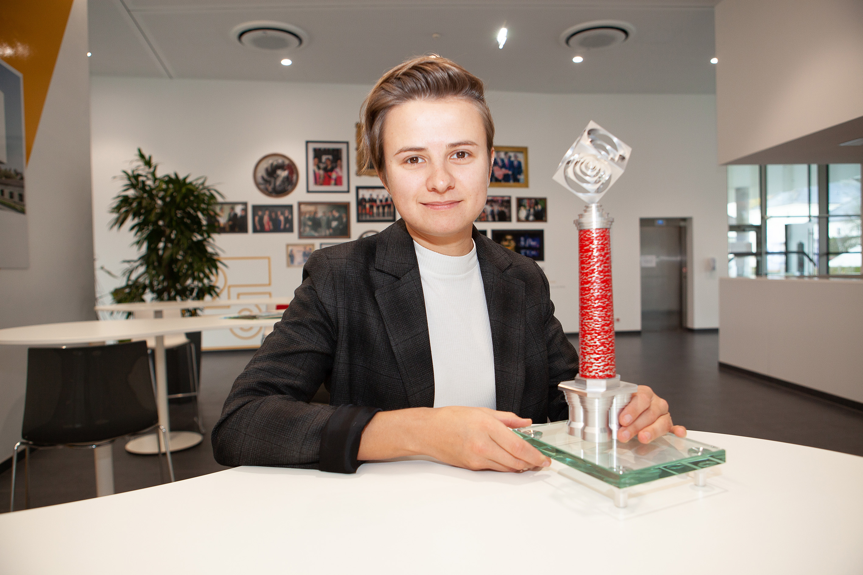 Denise Beil sitzt am Tisch mit dem Chimney Award in der Hand und blickt in die Kamera.