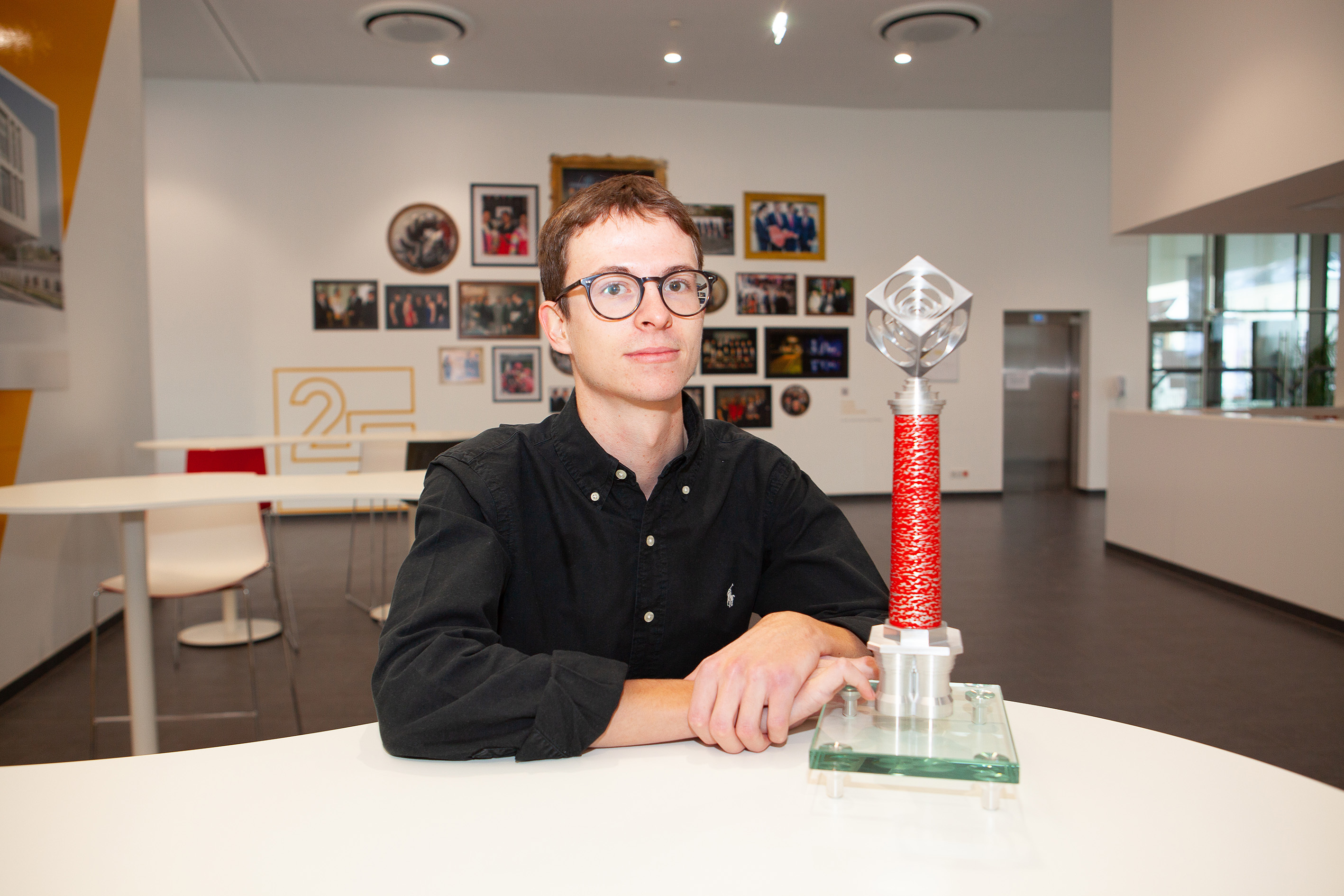 Janick Kern sitzt am Tisch mit dem Chimney Award neben sich und blickt in die Kamera.
