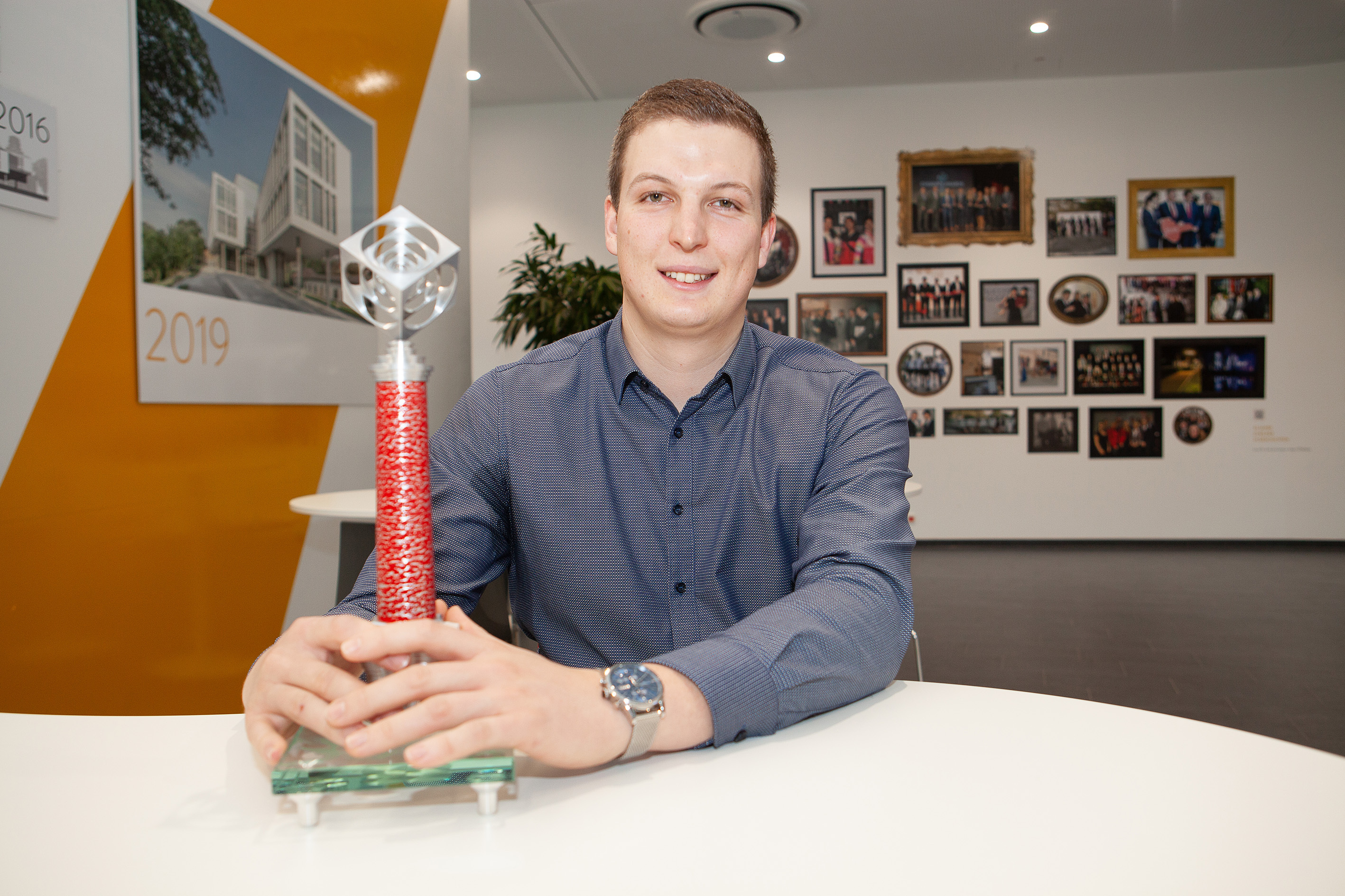 Alexander Strauss hält den Chimney Award in der Hand und blickt in die Kamera