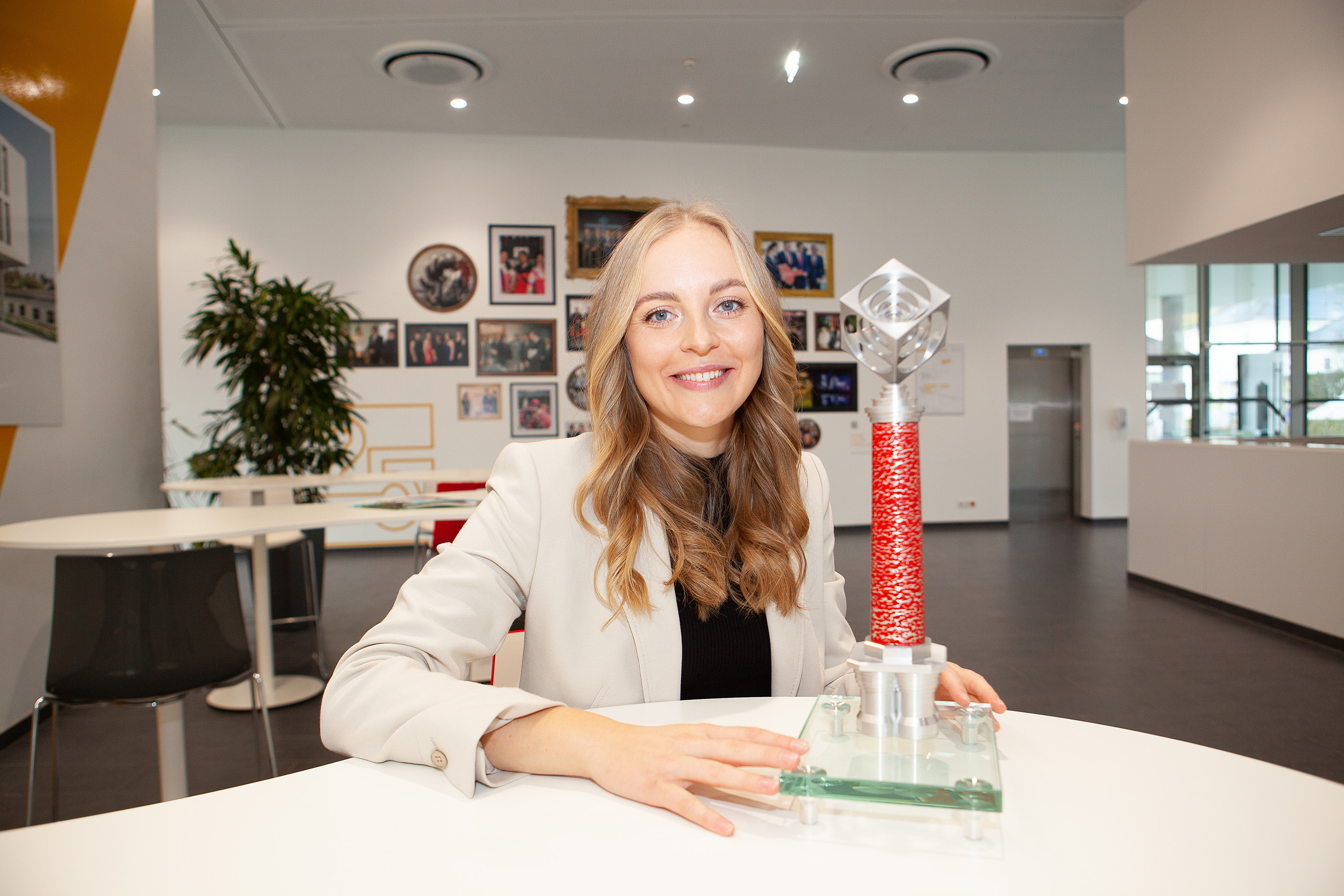 Victoria Bauer sitzt am Tisch mit dem Chimney Award in der Hand und blickt in die Kamera.