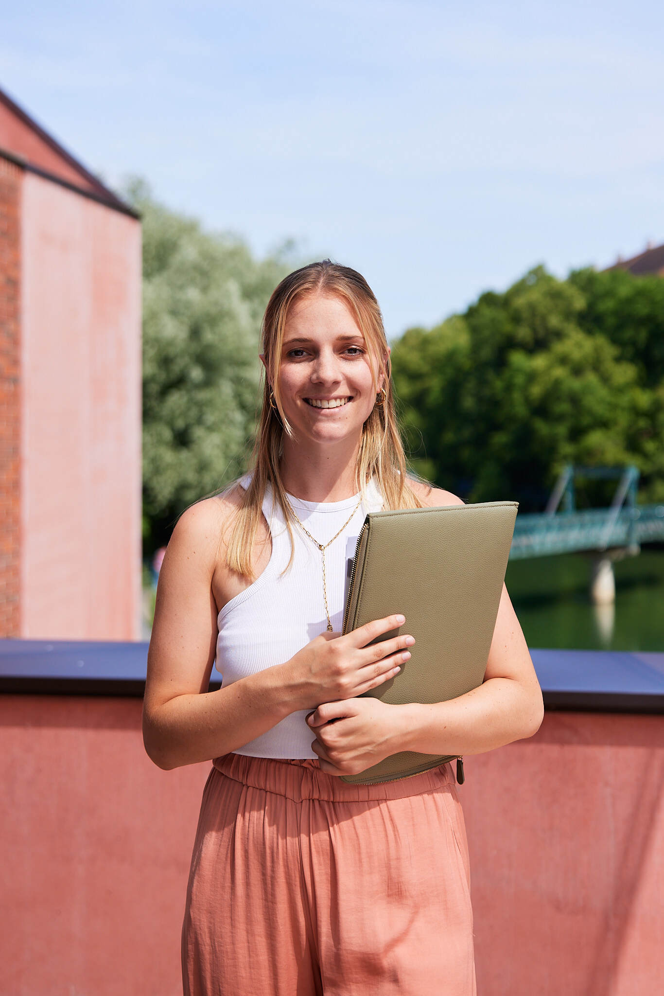 Eine junge Studentin wird von komplett von mit einem Laptop in ihrer Hand abgebildet.
