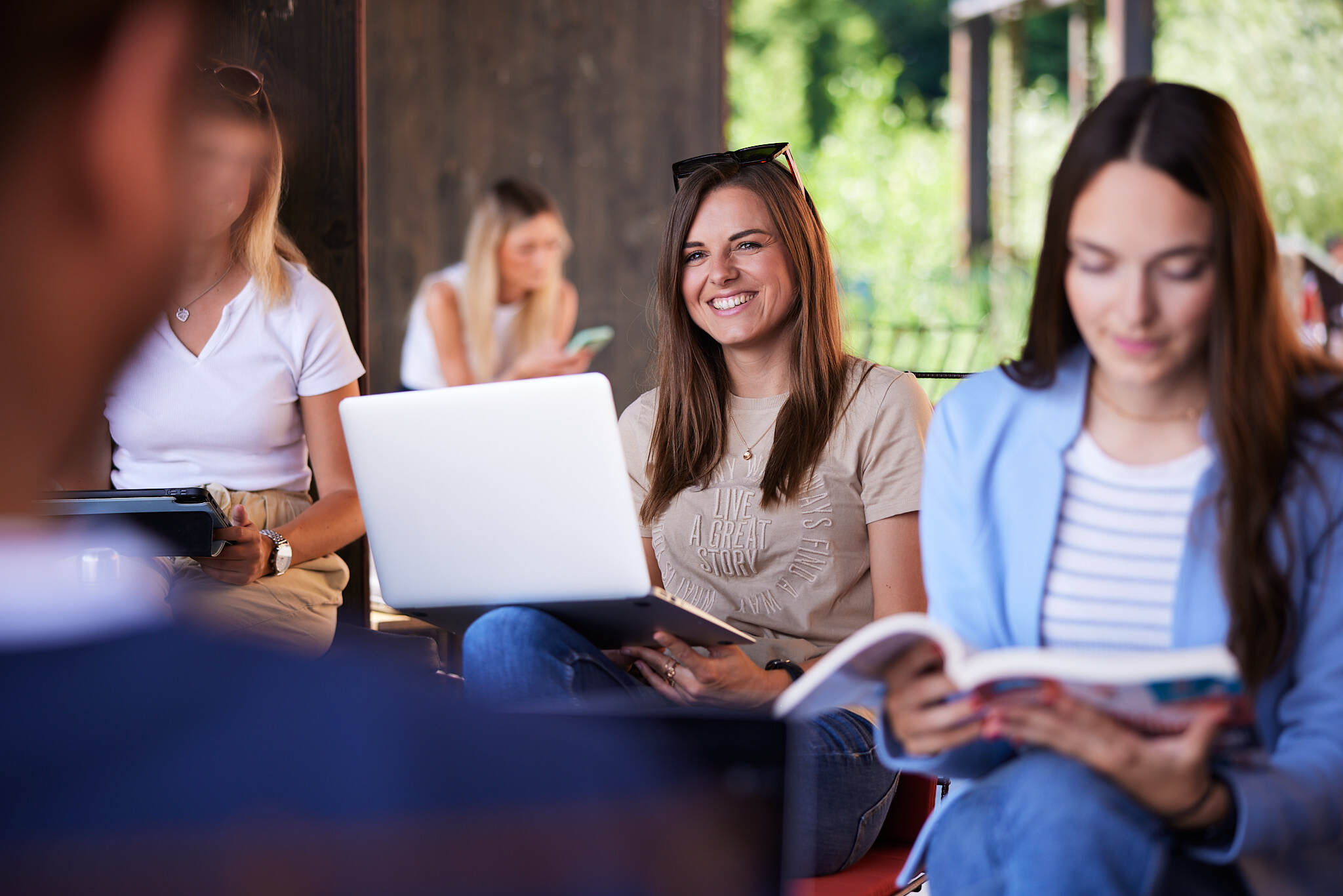eine Studentin in einem Outdoor-Bereich der FH Steyr ist im Fokus während die anderen Studenten unscharf sind.
