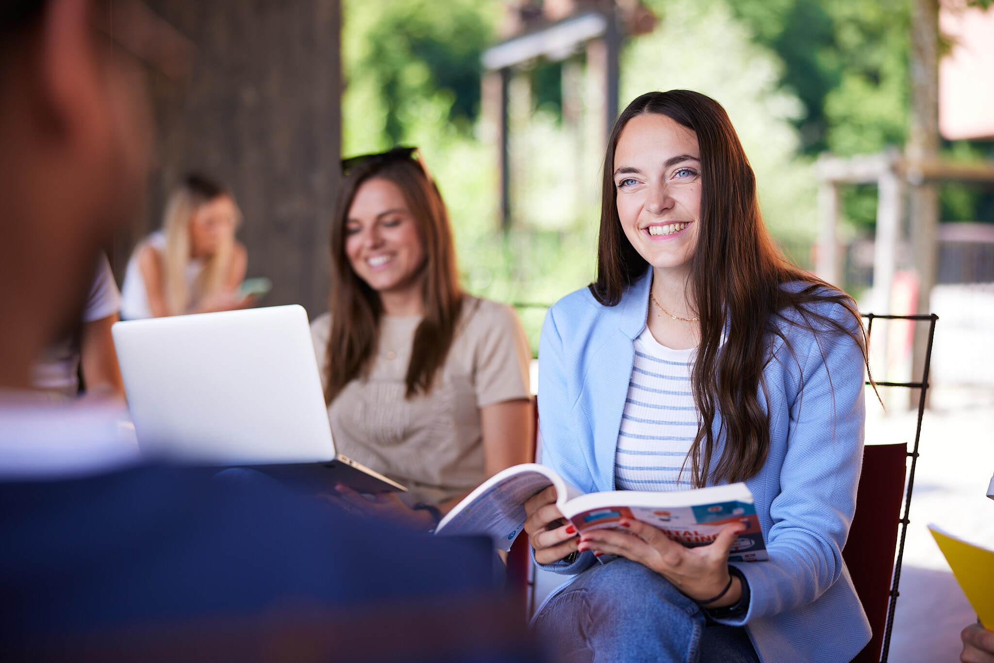 eine Studentin in einem Outdoor-Bereich der FH Steyr ist im Fokus während die anderen Studenten unscharf sind.