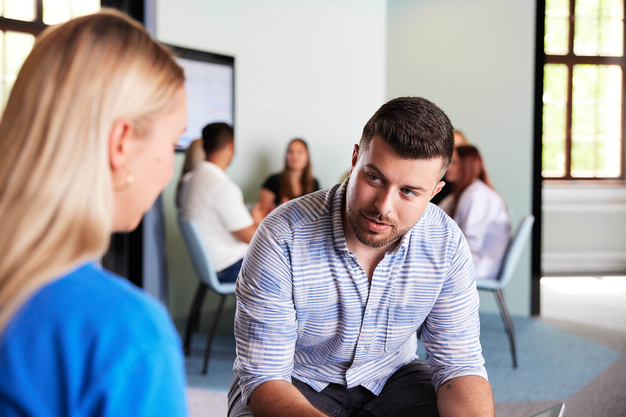Ein junger Student unterhält sich mit einer Studentin in einem Aufenthaltsraum der FH Steyr