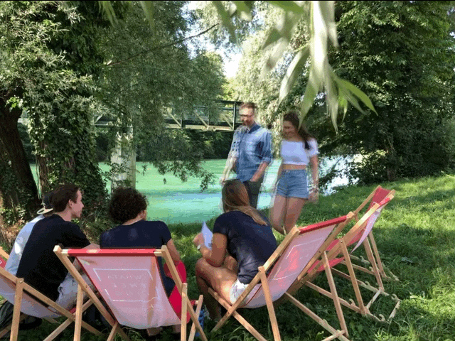 Foto einer Gruppe von Studierenden die auf Liegestühlen am Fluss sitzen