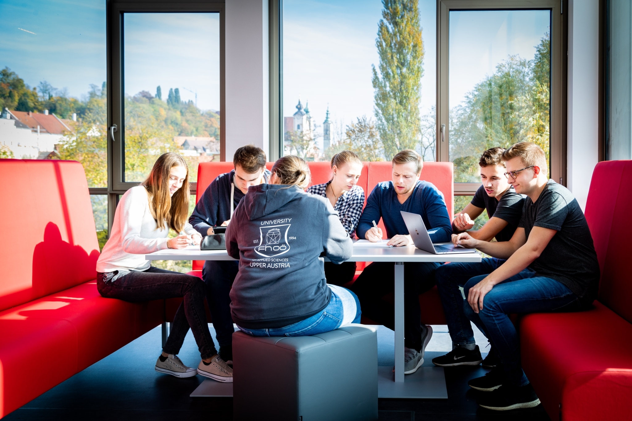 Mehrere Studierende sitzen zusammen an einem Tisch und arbeiten gemeinsam an einer Gruppenaufgabe