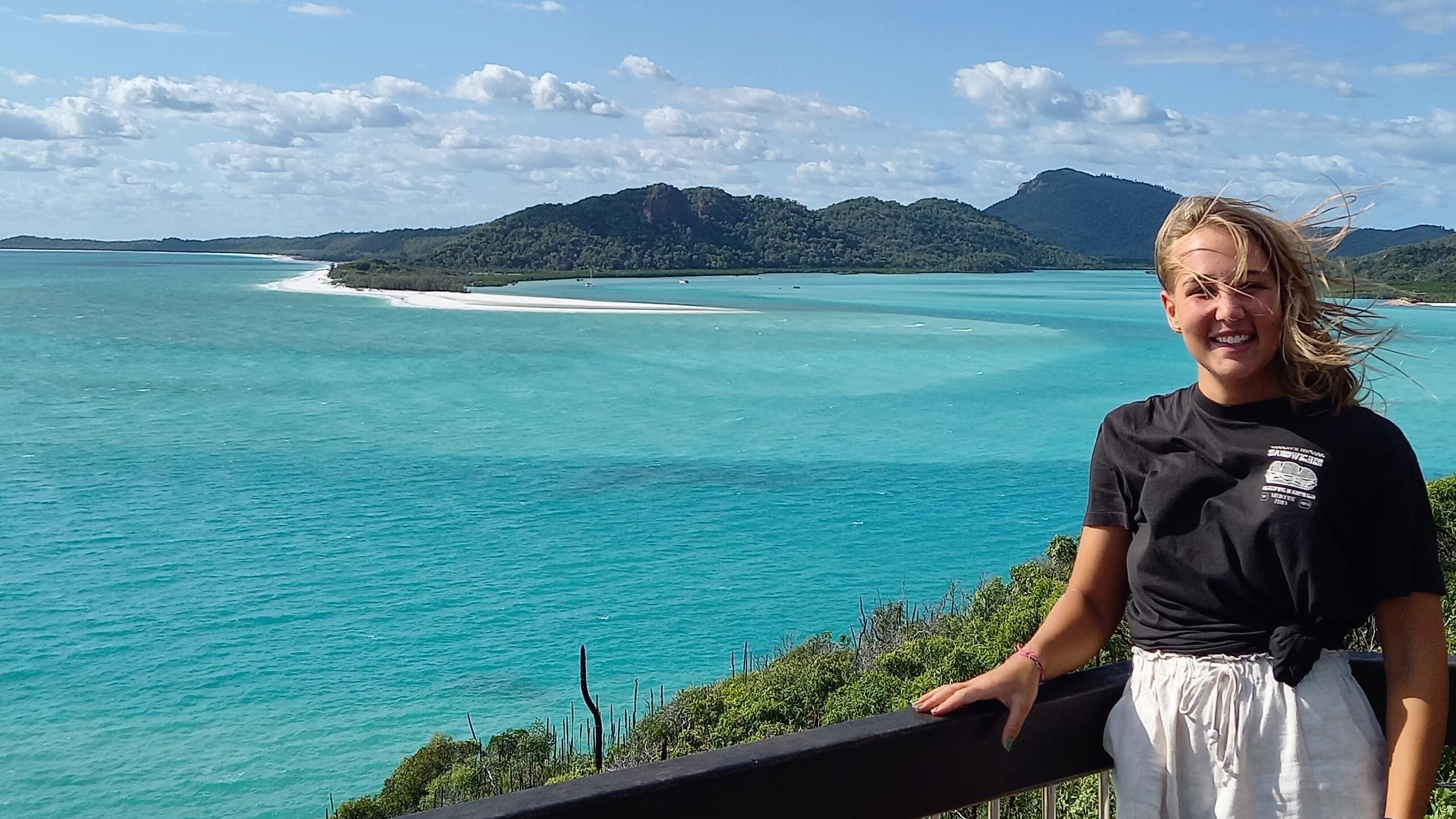 Eine Studentin steht an einem Aussichtspunkt, im Hintergrund ist das türkis-blaue Meer zu sehen