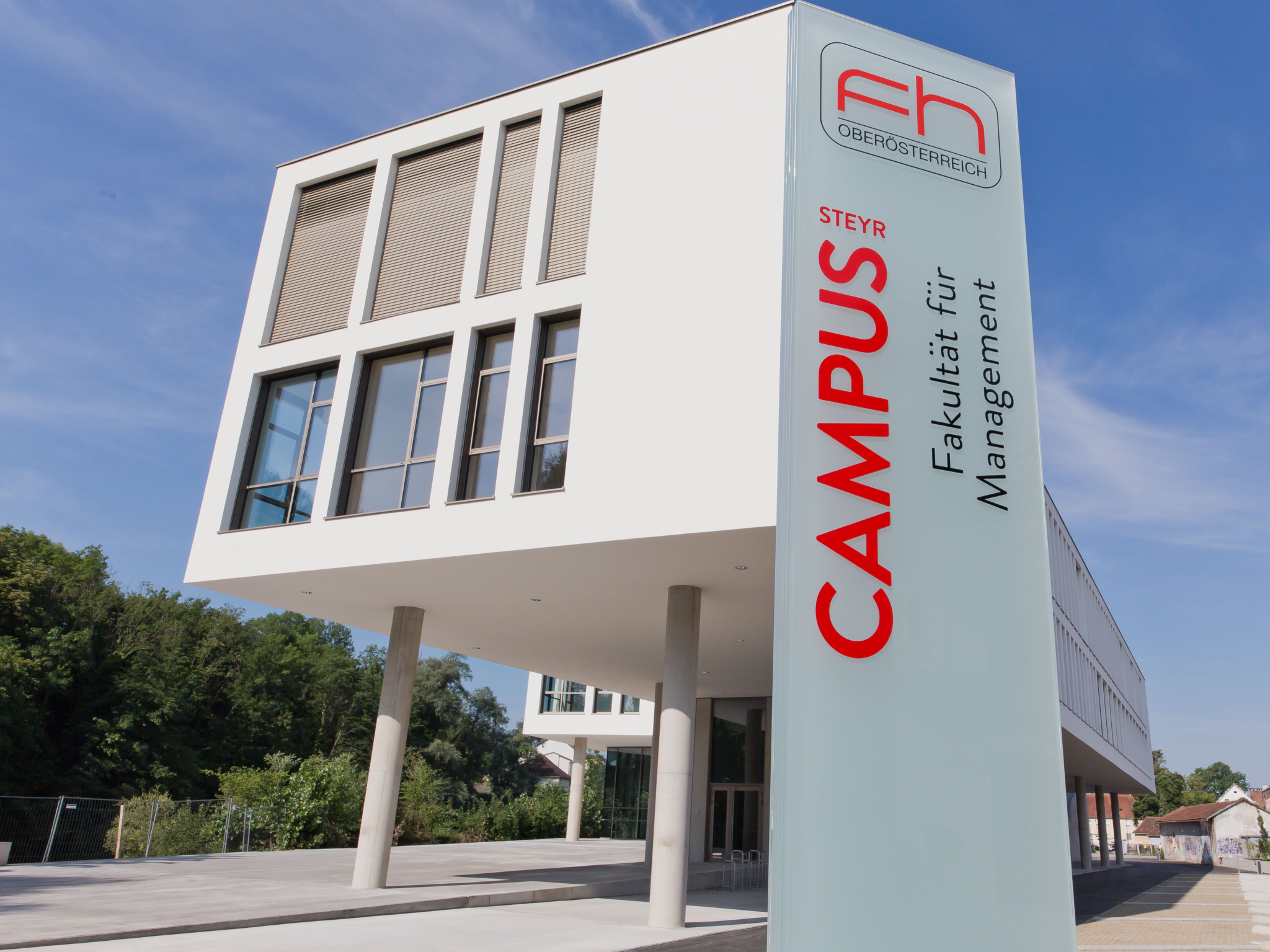 Foto des FH3-Gebäudes am Campus Steyr mit Fokus auf ein Schild, auf dem
"Campus Steyr – Fakultät für Management‘"steht