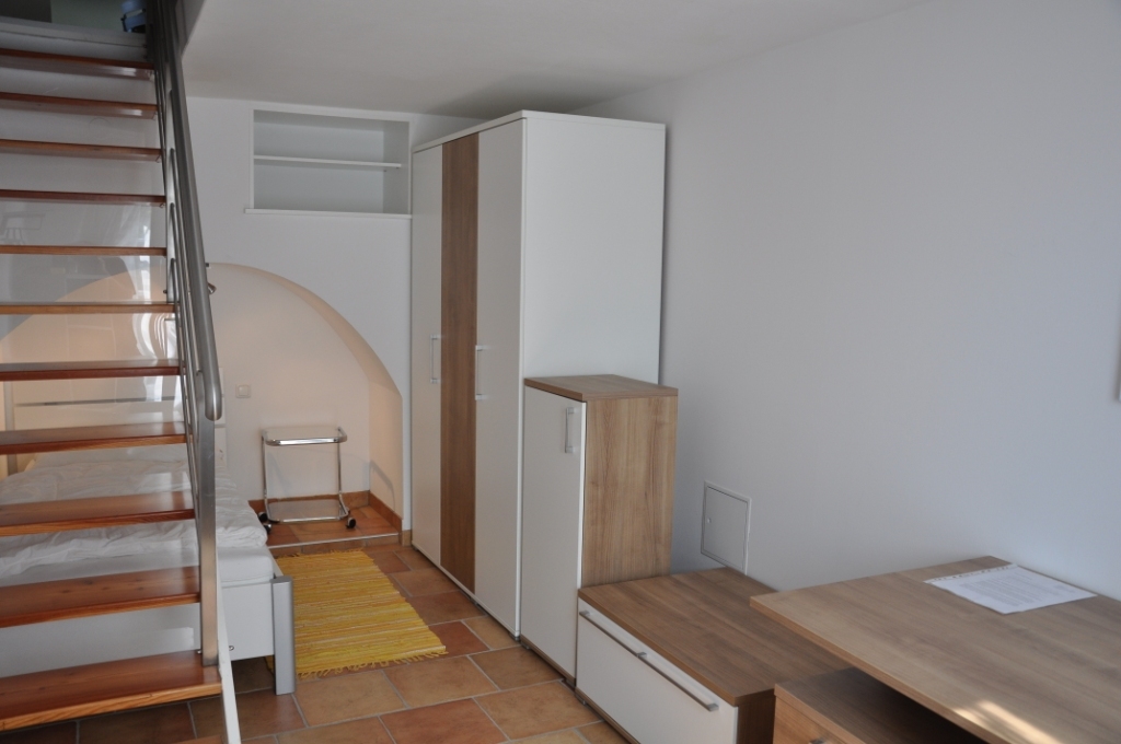 Teilansicht eines möblierten Studentenzimmers mit Bett und Kleiderschränken.