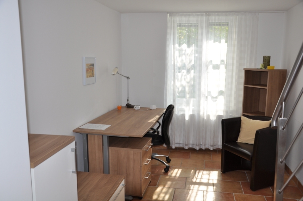 Innenaufnahme eines Arbeitsbereichs in einer Studenten-WG mit Schreibtisch, Stuhl und Regal im Bild