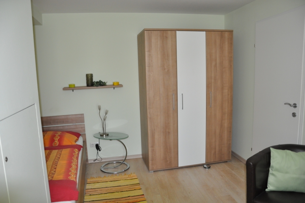 Teilansicht eines Studentenzimmers mit Bett, Kleiderschrank und Stuhl