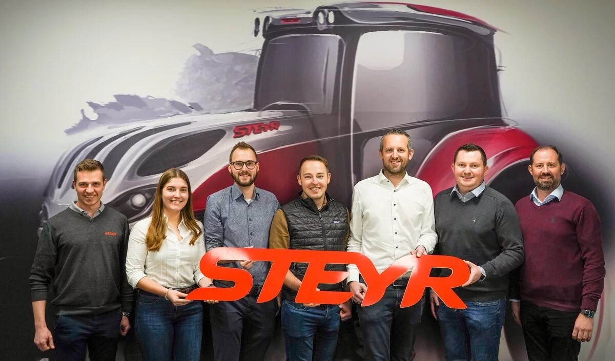 Auf dem Foto hält eine Gruppe Studierender und Professoren das Logo von Steyr Traktoren in den Händen und lächelt für ein Gruppenfoto.
