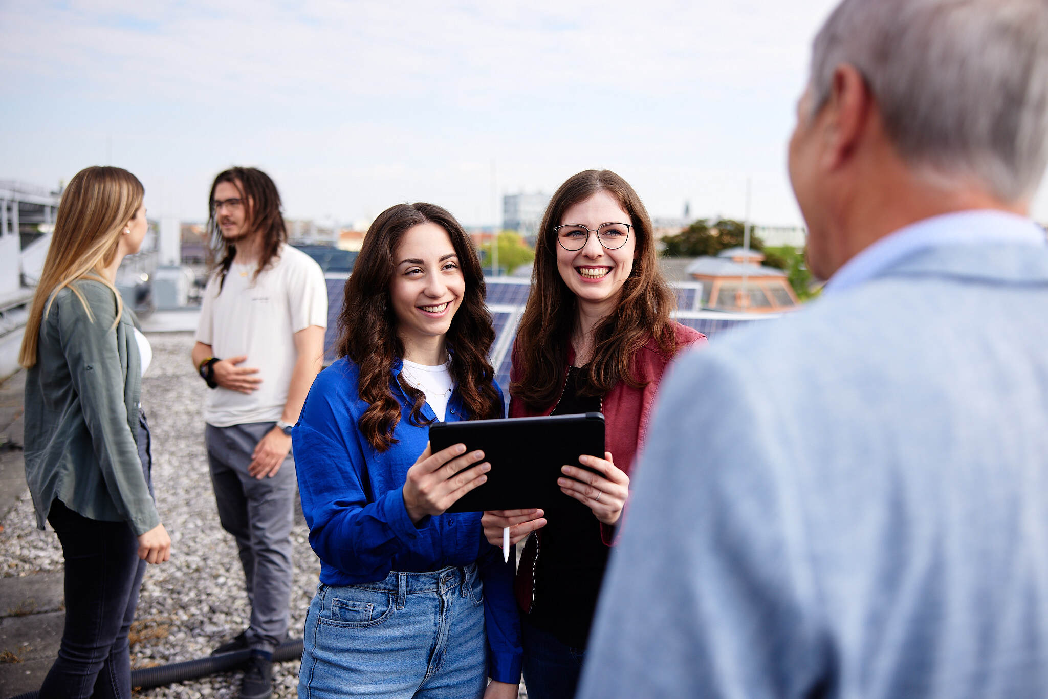 Eine gruppe junger Studentinnen bei einer Besprechung mit einem Professor auf dem Dach der FH Wels