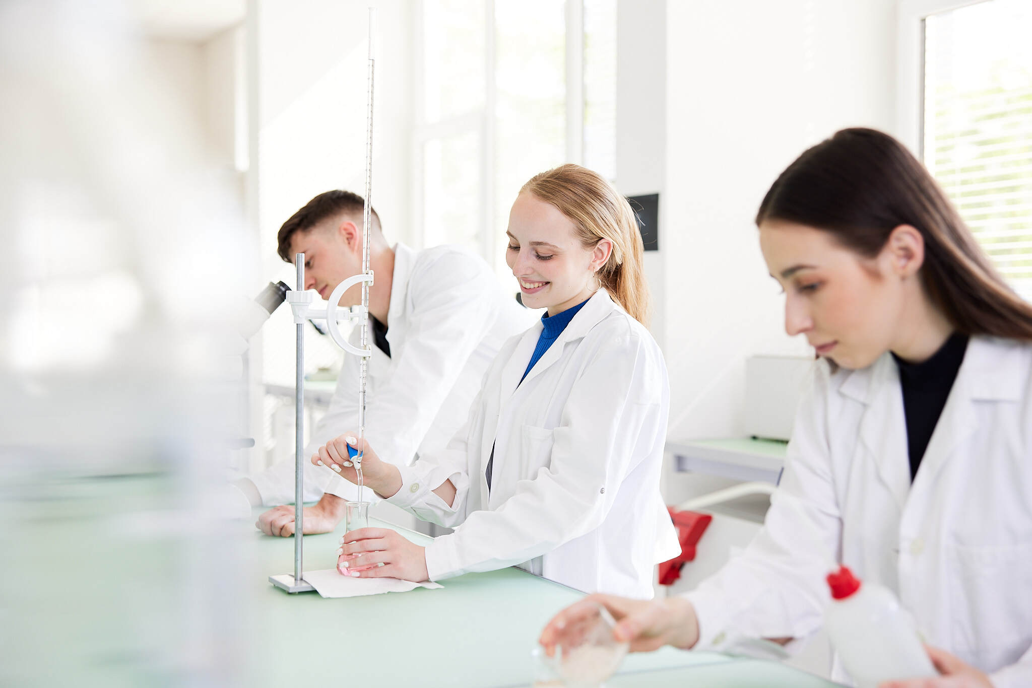 drei junge Studenten werden bei Versuchen in einem Labor gezeigt