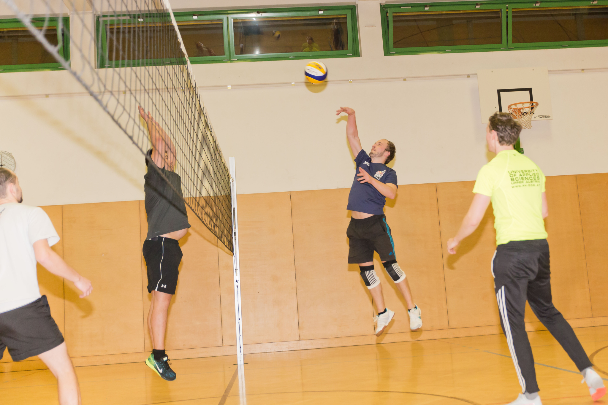 Eine Gruppe an Studenten am Volleyball spielen.