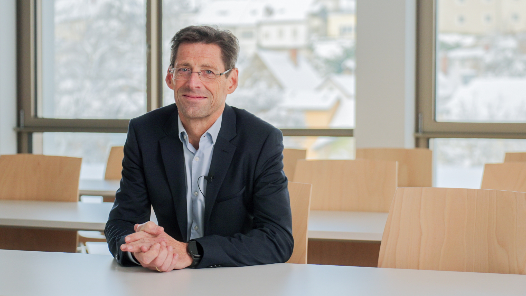 Dr. Heimo Losbichler sitzt am Tisch in einem Seminarraum und blickt in die Kamera