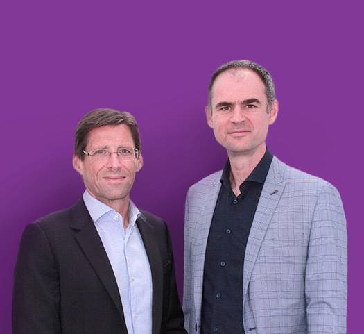Dr. Heimo Losbichler (links) und Dr. Christoph Eisl (rechts) stehen nebeneinander vor einem lila Hintergrund.