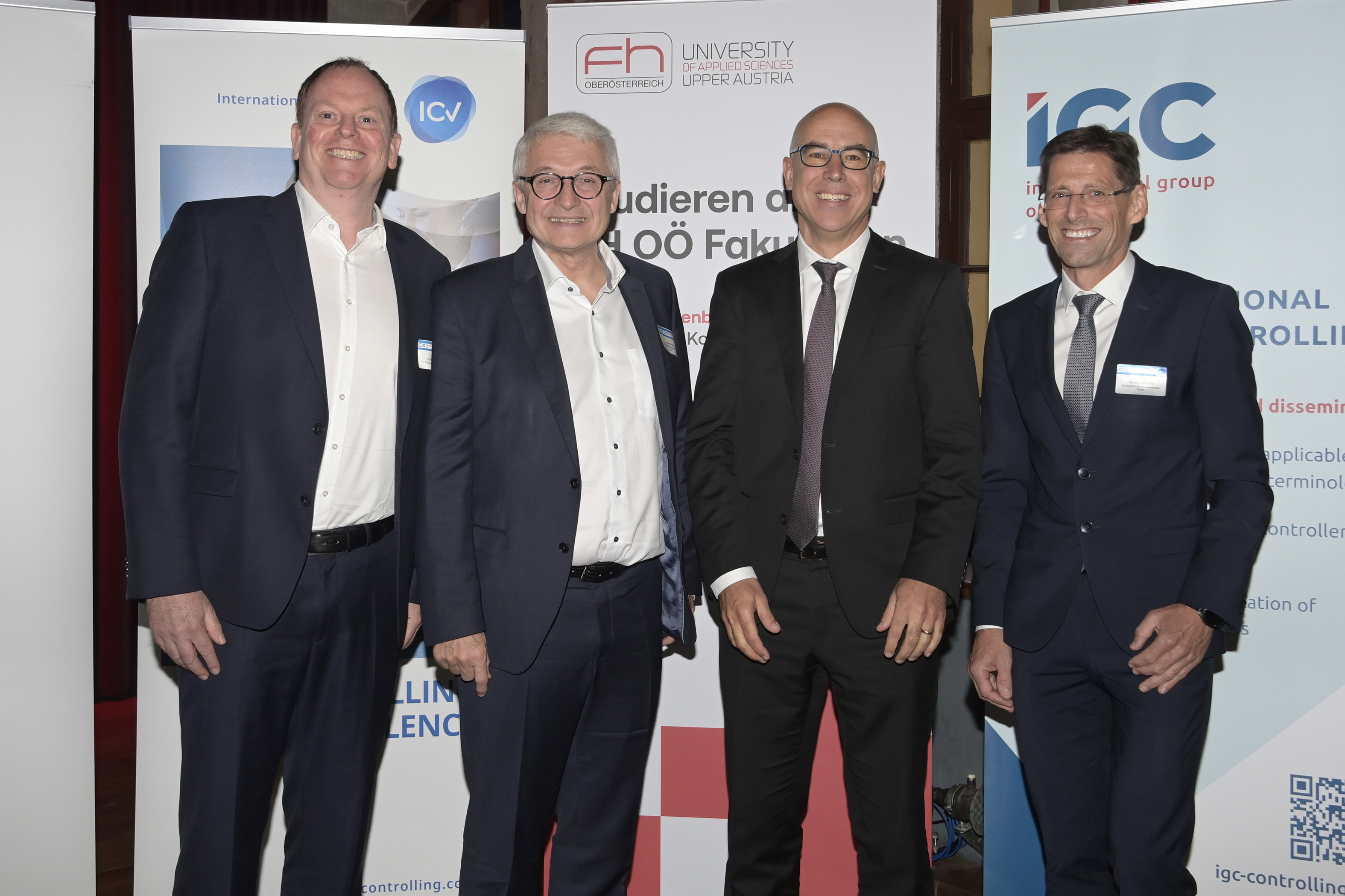 Vier Männer in Anzügen stehen vor Informationsaufstellern der FH Oberösterreich, des Internationalen Controller Vereins (ICV) und des International Group of Controlling (IGC)