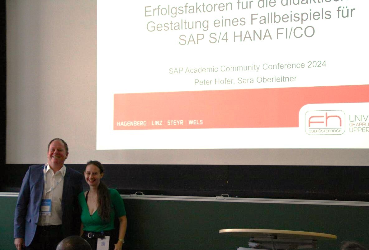 FH-Professor Peter Hofer und die ehemalige CRFM-Studentin Sara Oberleitner lachen in die Kamera.