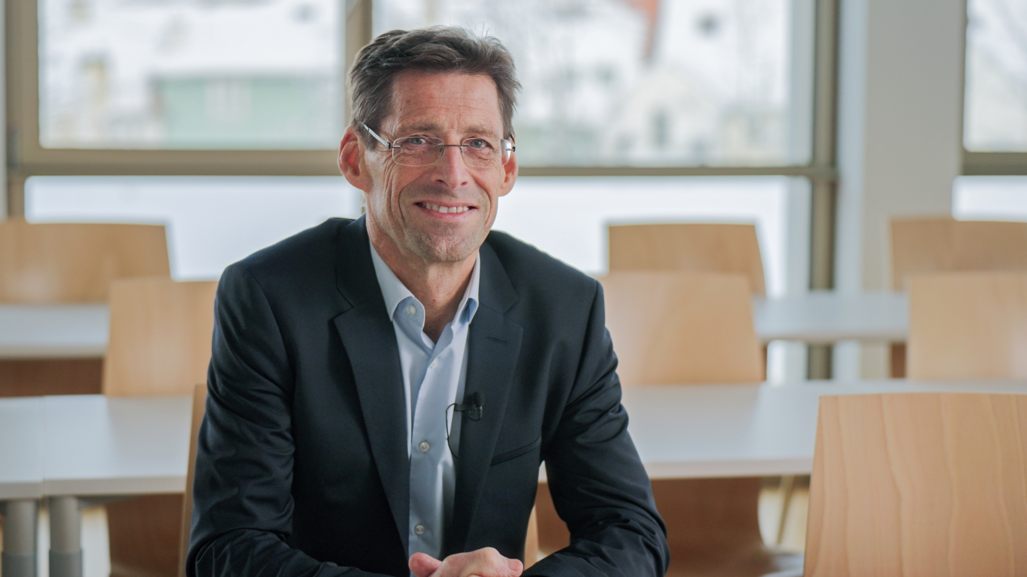 Dr. Heimo Losbichler sitzt in einem Seminarraum und lächelt in die Kamera