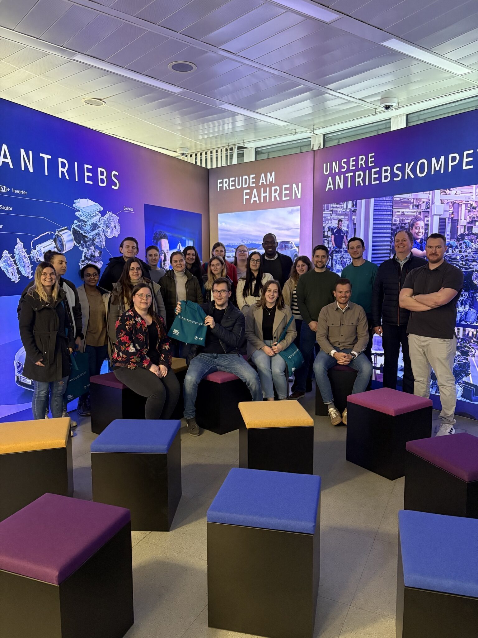 Eine Gruppe von Studierenden posiert für ein Foto in einem Innenraum der BMW Group in Steyr im Rahmen einer Exkursion.