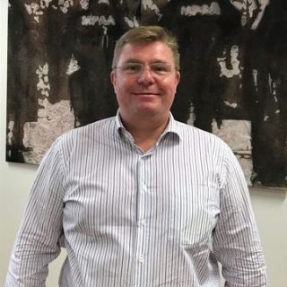 Porträtfoto von Mag. Matthias Schulmeister, der vor einer Wand steht