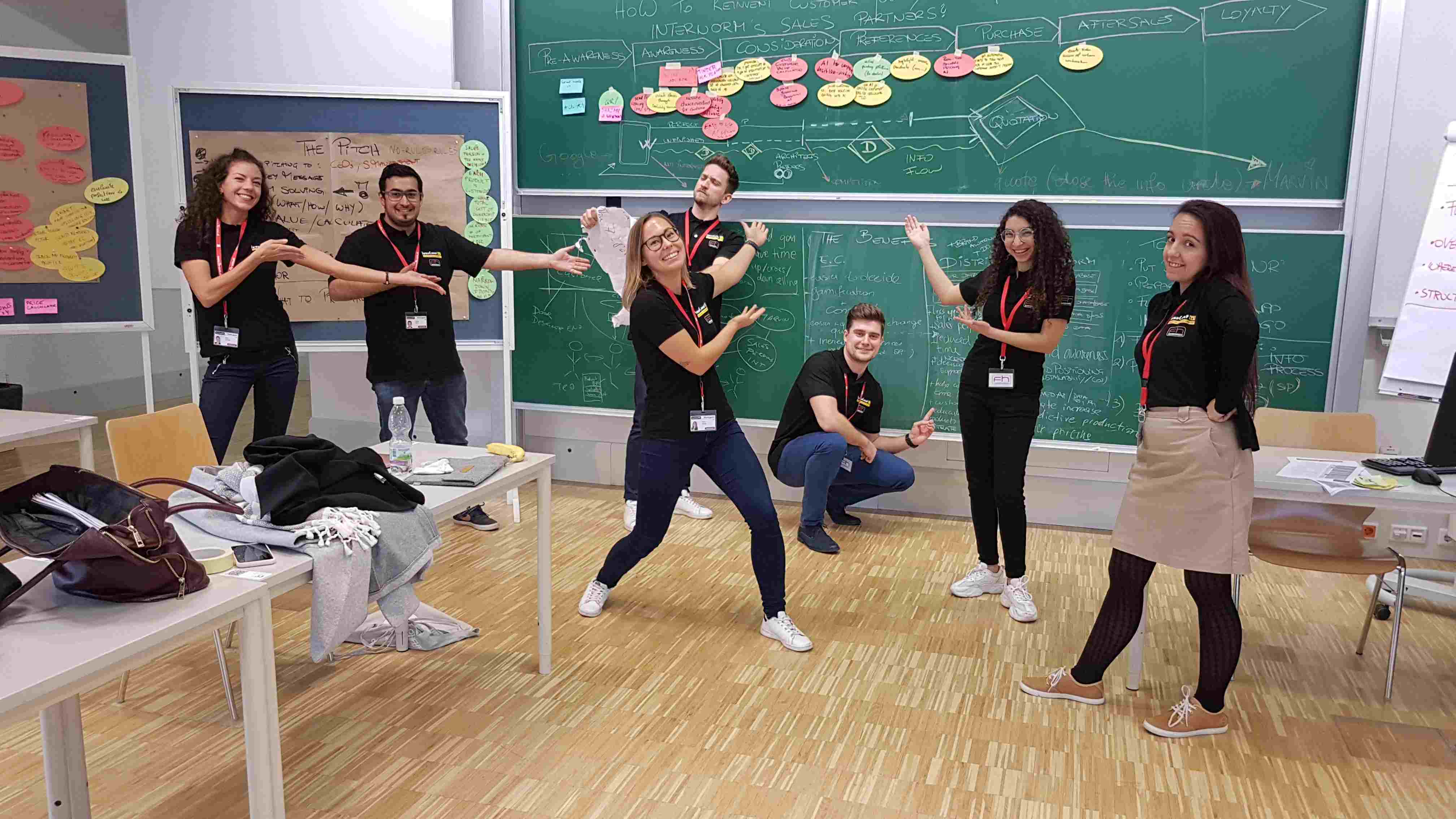 A group of students poses in front of a whiteboard in a seminar room.