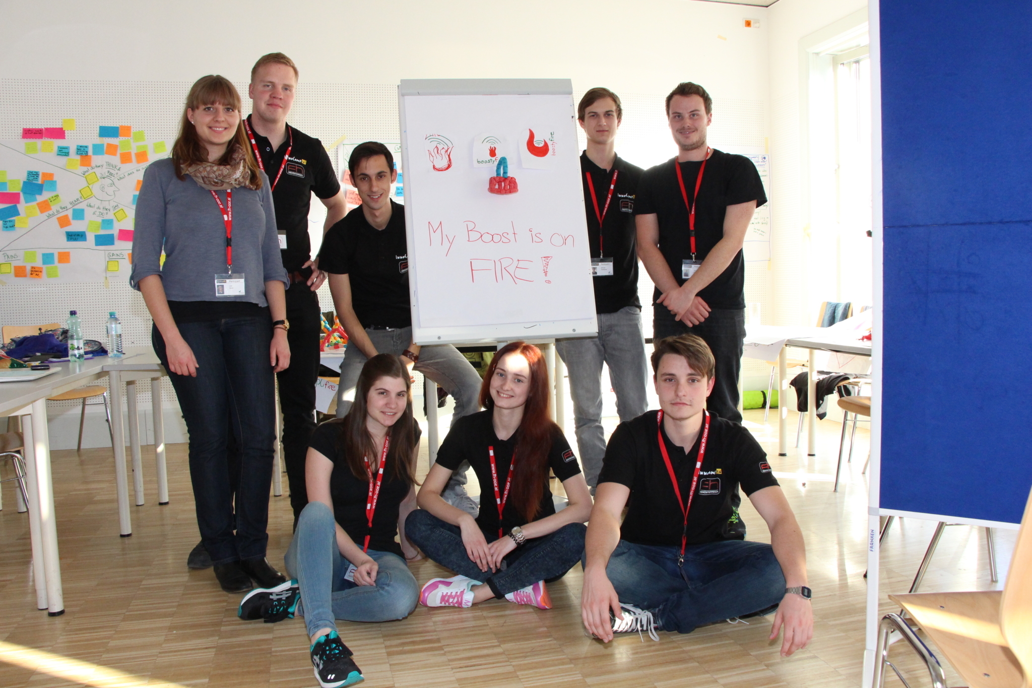 A group of students posing in a bright room with a flipchart that says "My Boost is on FIRE!"