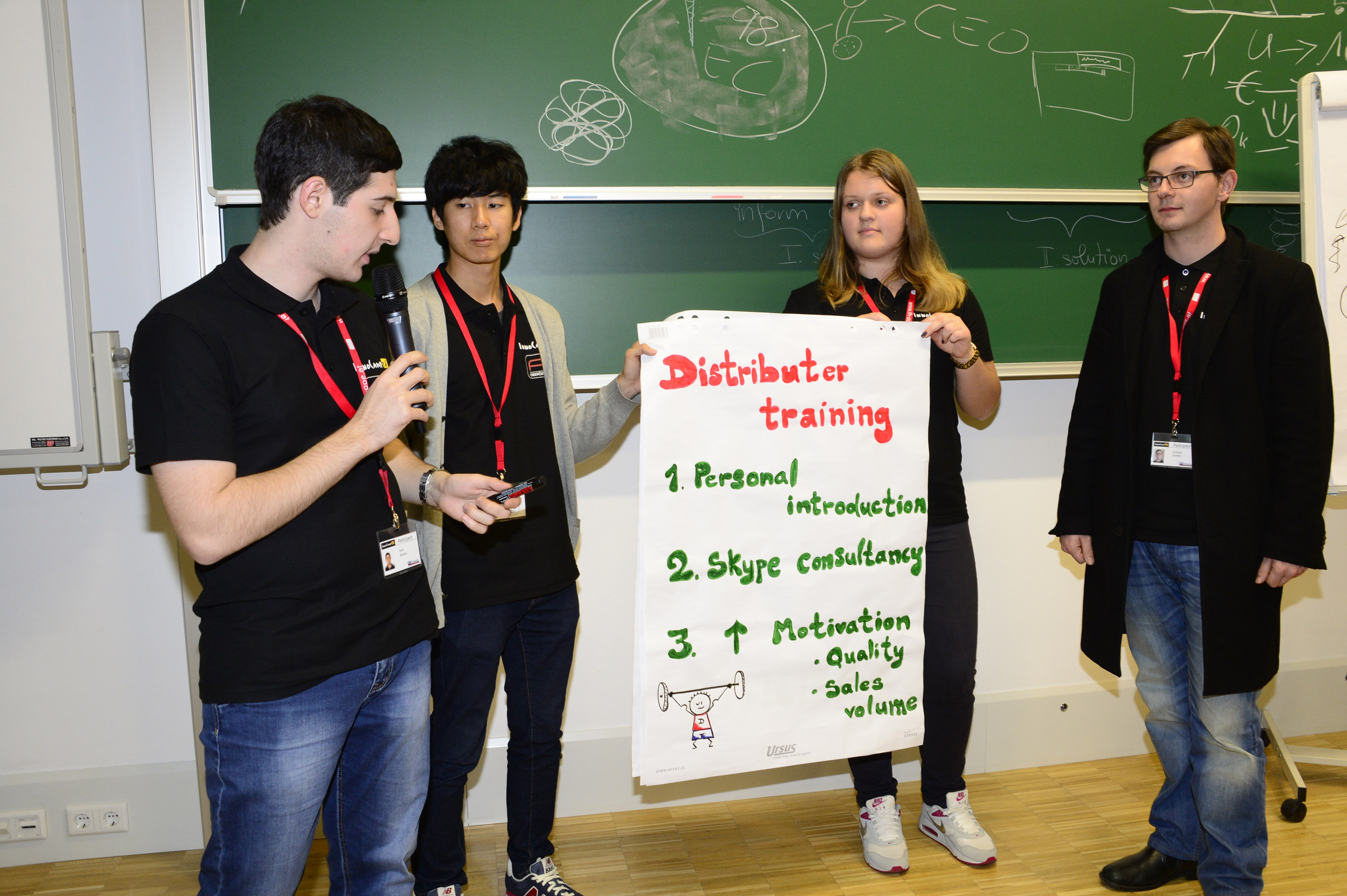 Four students stand in front of a blackboard and present a flipchart.