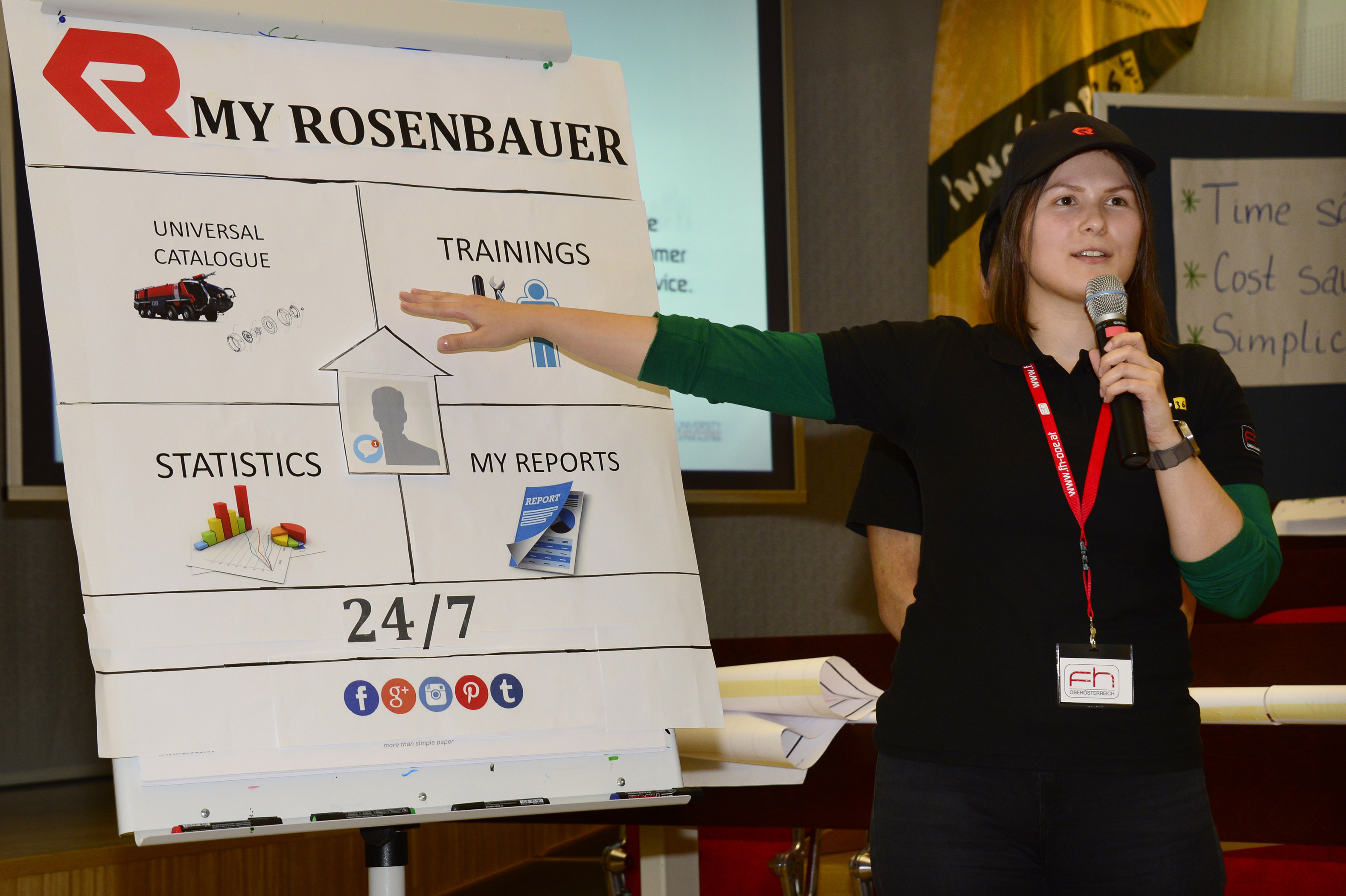A student is standing next to a flipchart with a microphone in her hand and giving a presentation.