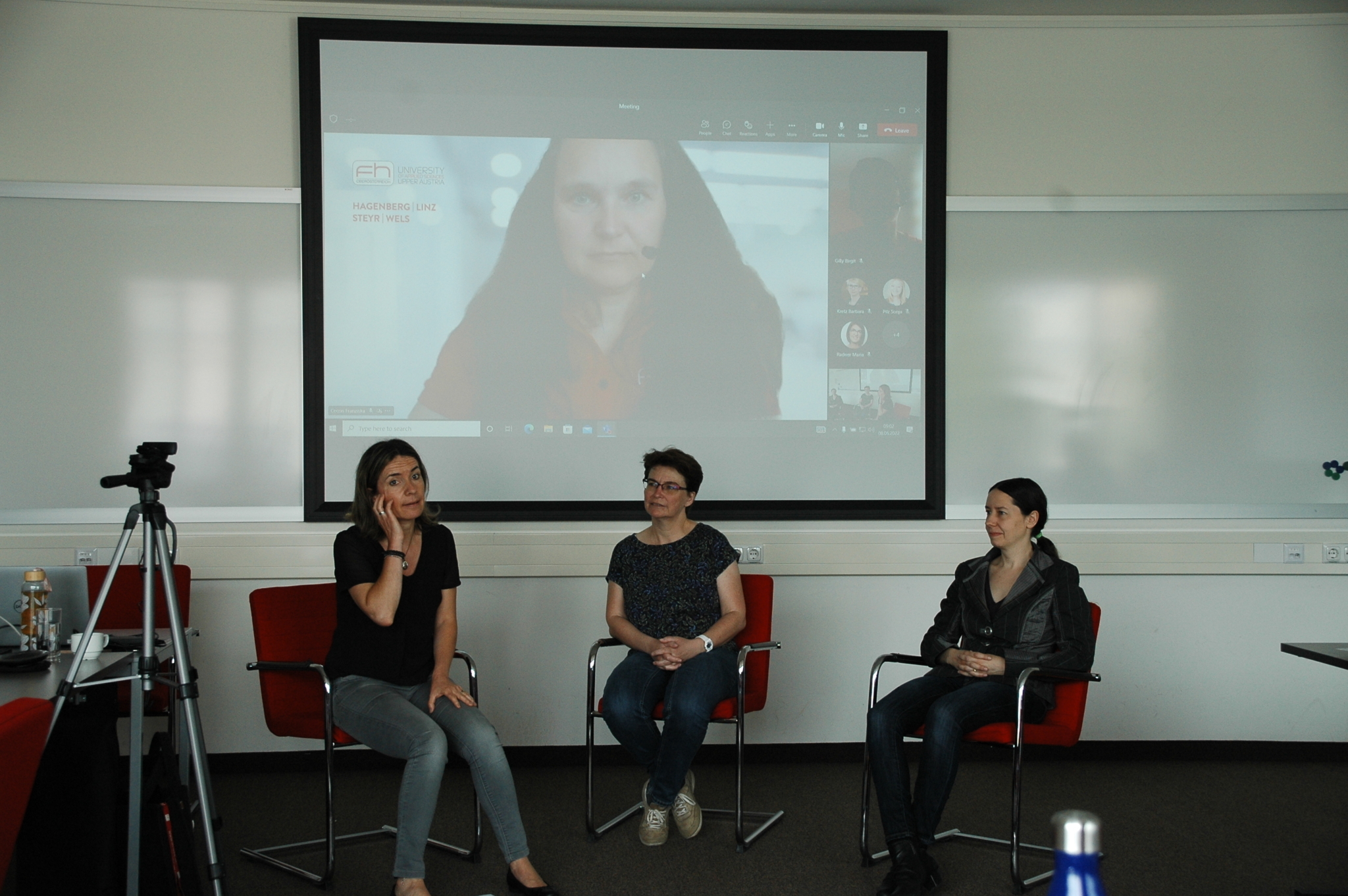 Ausschnitt einer Besprechung des Frauennetzwerkes. Drei Damen sitzen vor einer auf die Wand projizierten Online-Konferenz.
