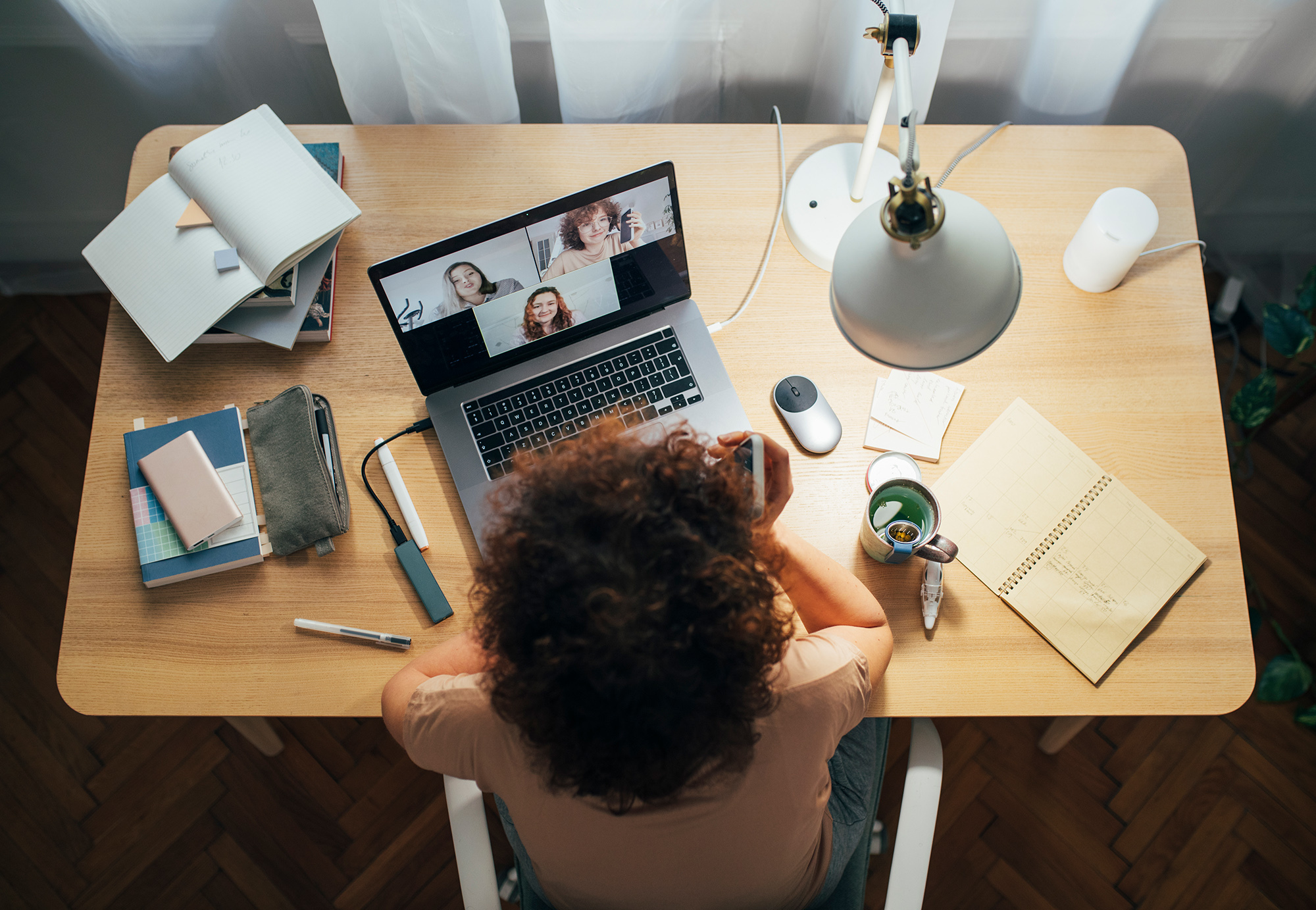 Eine junge Studentin sitzt vor ihrem Laptop und wird von oben gezeigt