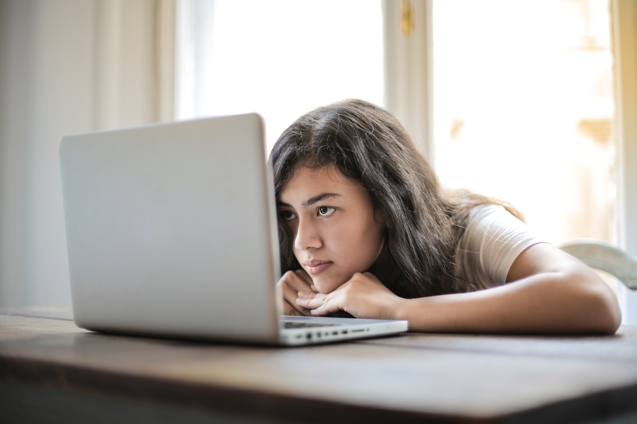 Studentin sitzt hinter ihrem Laptop und wird von der Seite gezeigt