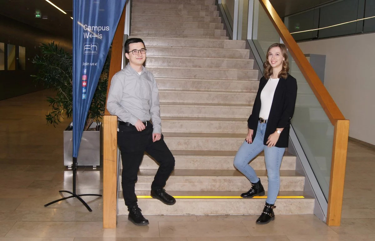 Ein Student und eine Studentin stehen auf einer Treppe