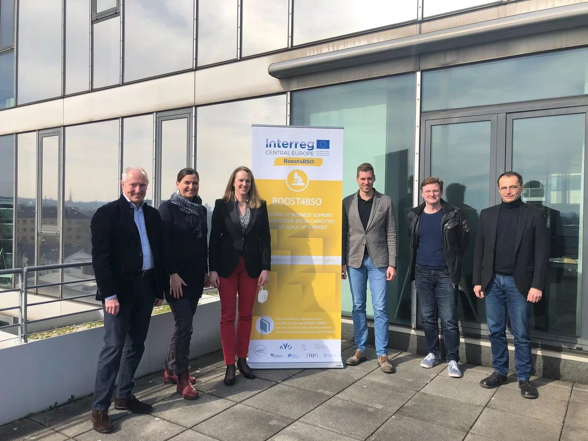 Zwei Frauen und vier Männer stehen vor einem Gebäude neben einem Banner mit der Aufschrift Interreg