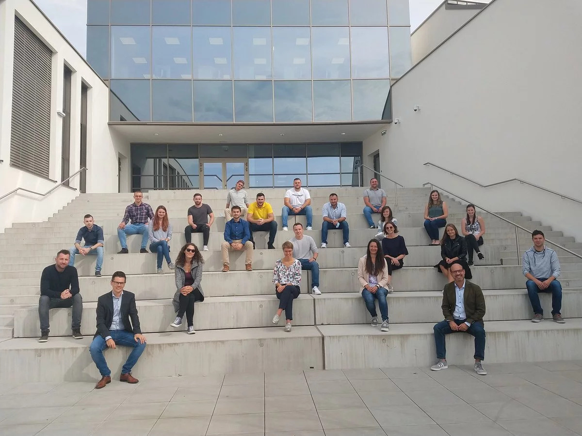 Eine Gruppe Studenten sitzt auf einer Betontreppe für ein Gruppenfoto