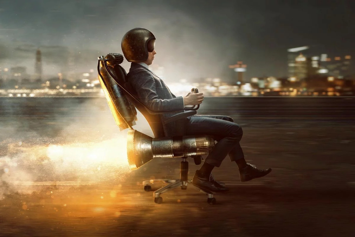 Ein Mann sitzt auf einem Bürostuhl, welcher mit einer Rakete betrieben ist