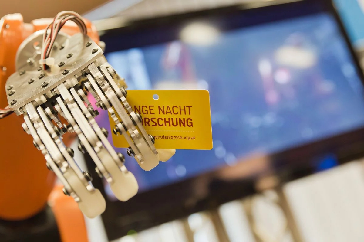 Eine Roboterhand hält ein Ticket für die lange Nacht der Forschung