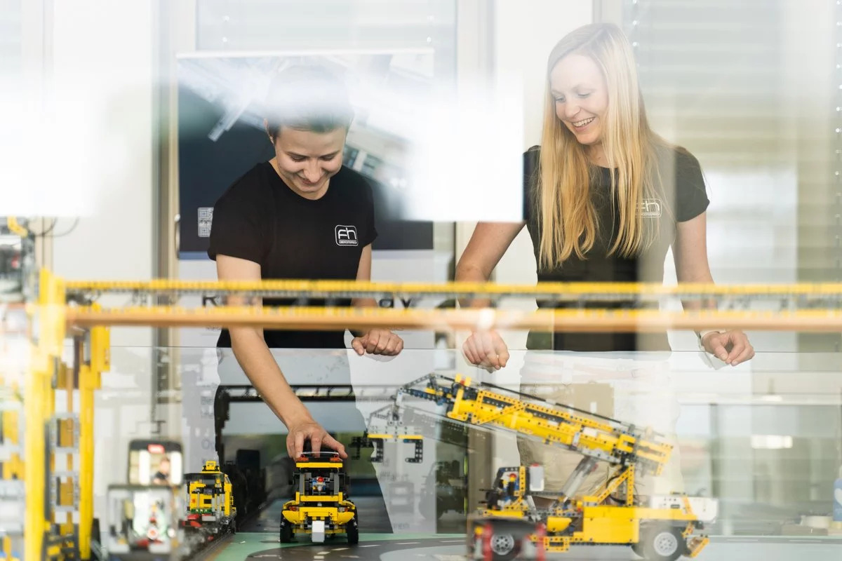 Zwei junge Frauen arbeiten mit kleinen elektronischen Robotern