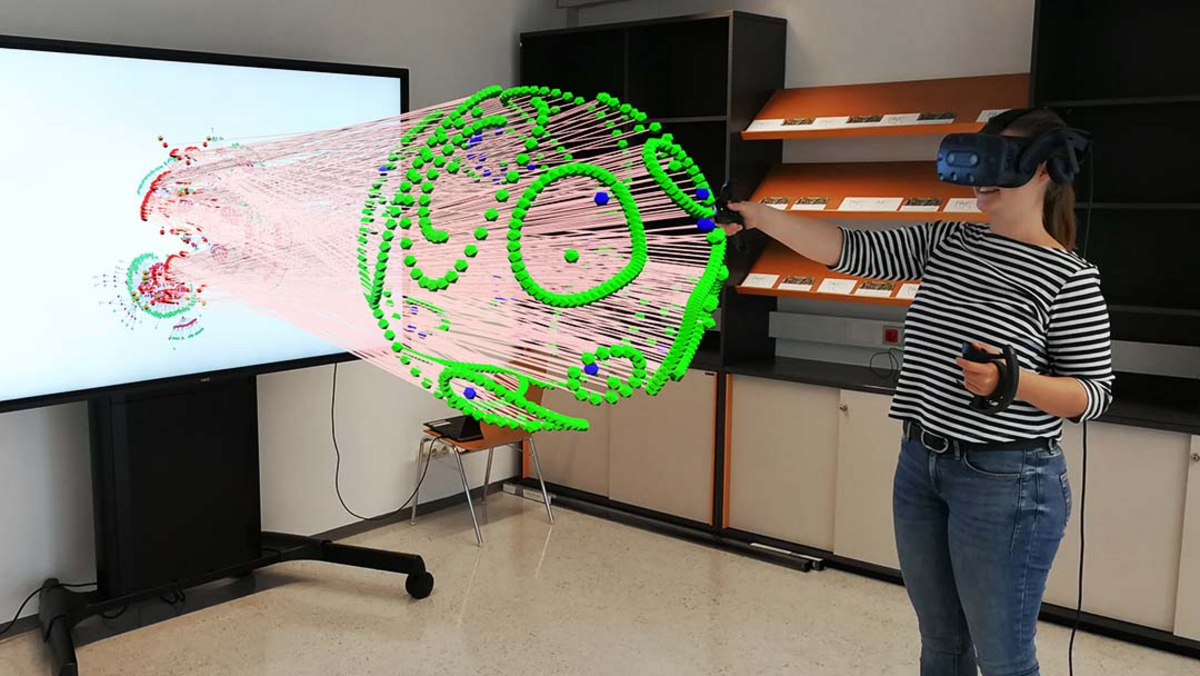 Eine Frau steht mit einer Virtual Reality Brille vor einem Fernseher. Inmitten des Raumes sieht man einen grünen Ball in 3D
