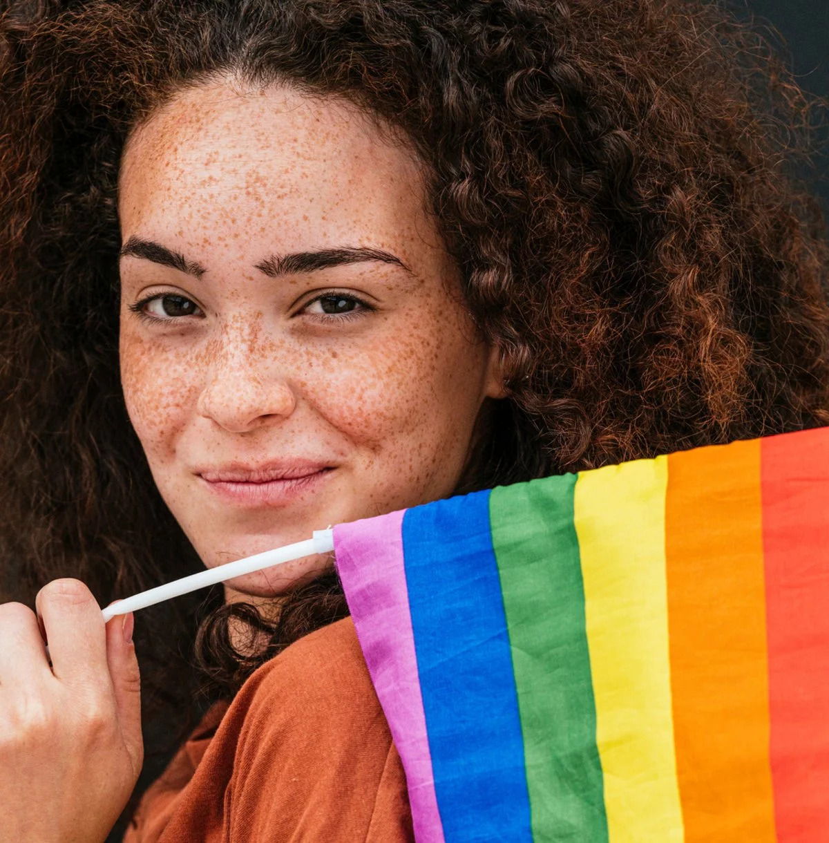 Eine Junge Frau hält eine Regenbogenflagge in der Hand