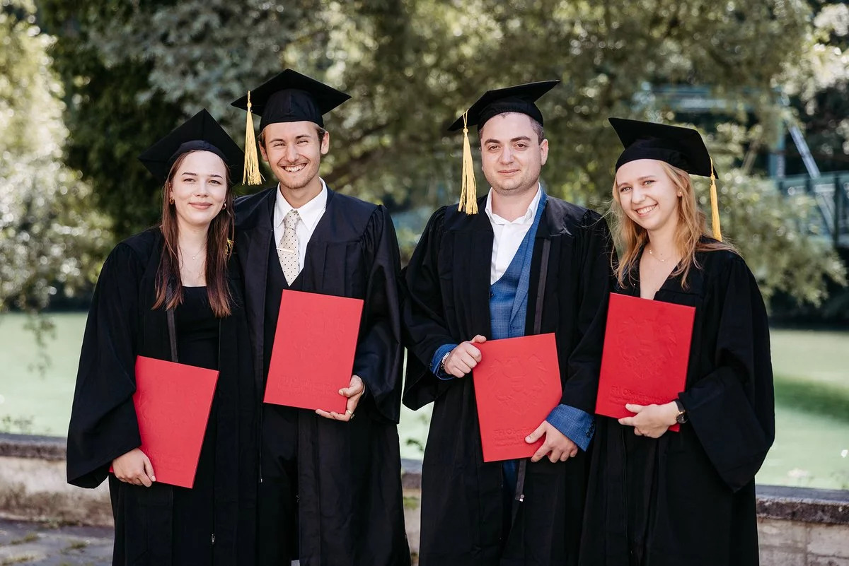Vier Absolventen mit roten Mäppchen