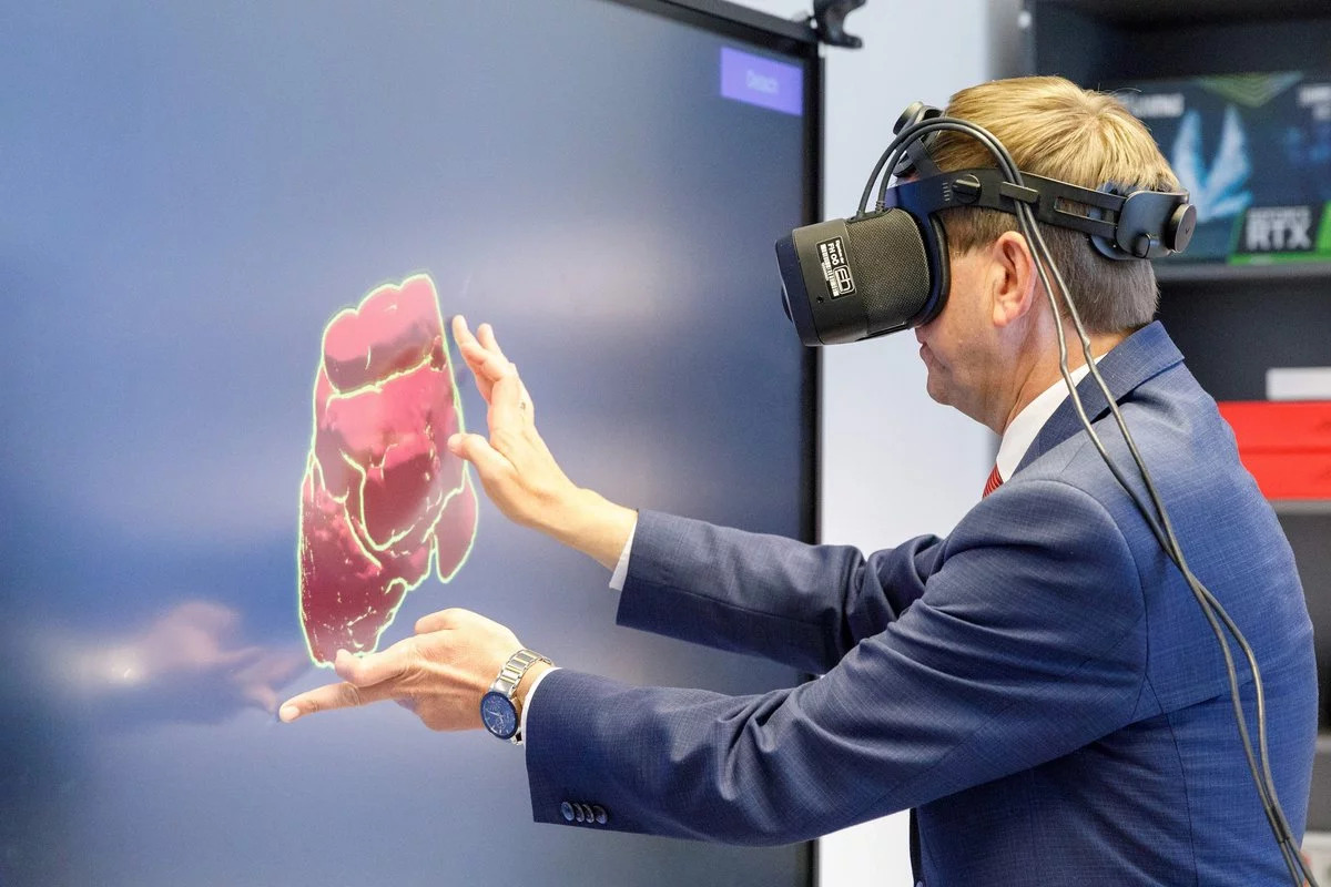 Ein Mann arbeitet an einem Fernsehbildschirm, während er eine Virtual Reality Brille trägt