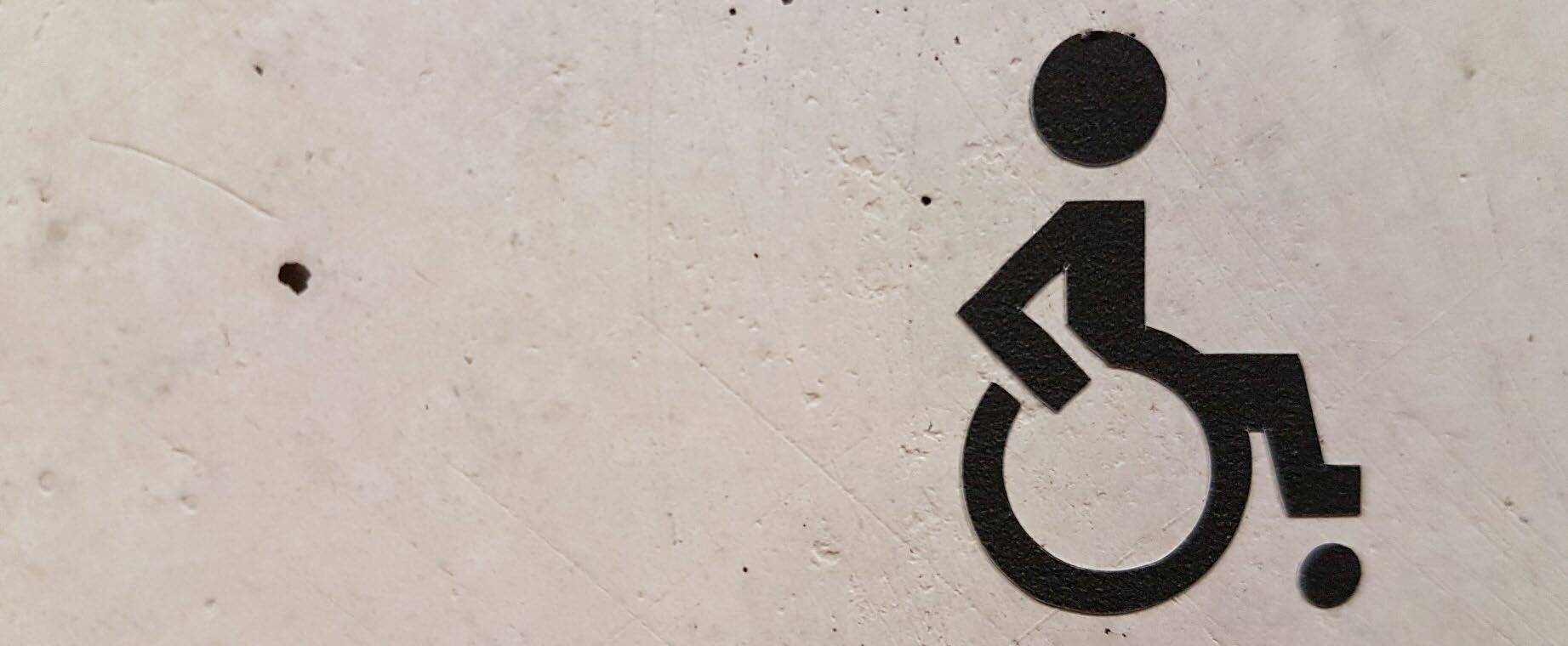 Ein auf dem Boden aufgemaltes Rollstuhlfahrer-Logo.