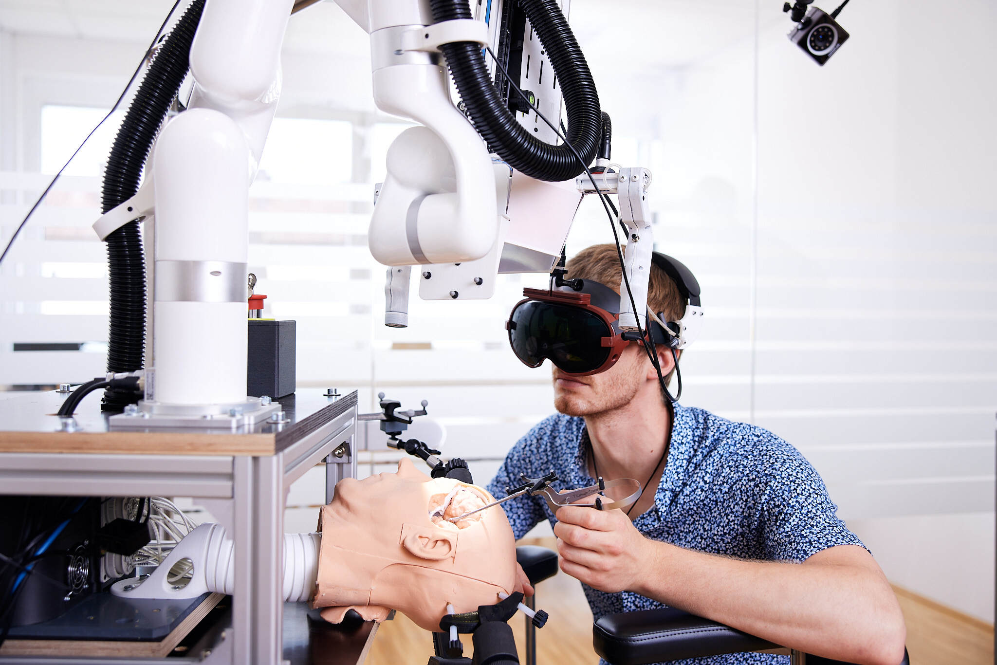 ein junger Student mit einem VR Headset operiert mit technischen Geräten an einem Test-Gehirn.